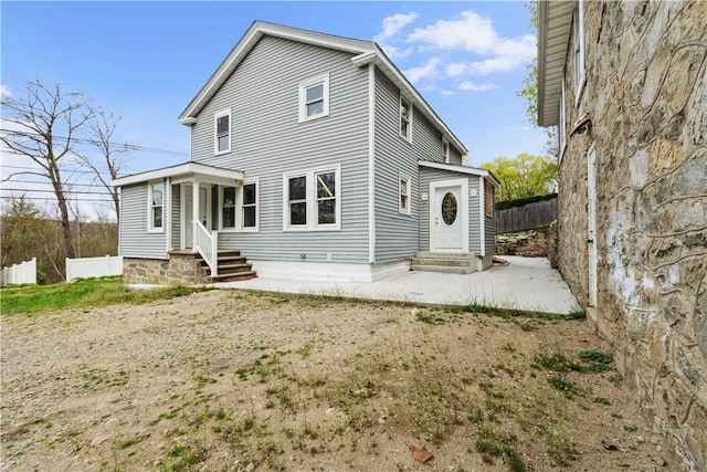 rear view of house featuring entry steps and fence
