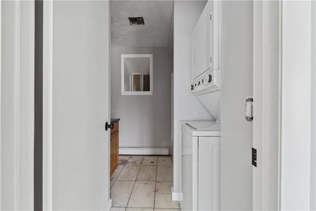 washroom with baseboard heating, stacked washer / dryer, and laundry area