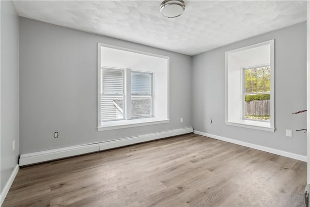 spare room with baseboards, wood finished floors, and a baseboard radiator
