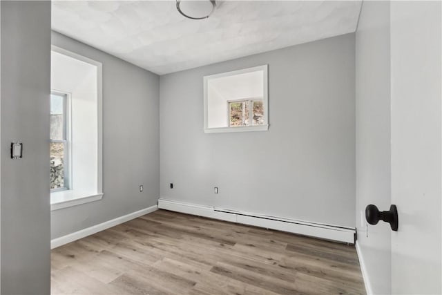 spare room featuring baseboard heating, baseboards, and wood finished floors