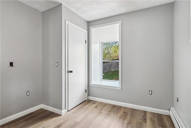 unfurnished bedroom featuring baseboards, light wood-style floors, and a baseboard radiator
