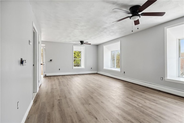 unfurnished living room with ceiling fan, baseboards, and a baseboard radiator