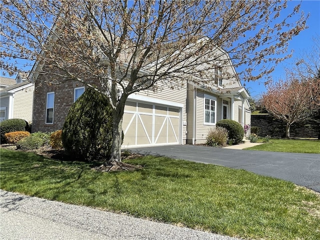 view of side of home featuring a yard, an attached garage, and aphalt driveway