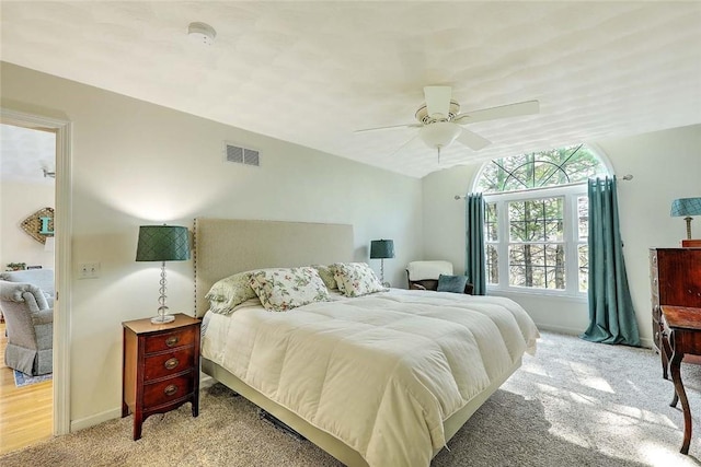 bedroom featuring a ceiling fan, visible vents, light carpet, and baseboards