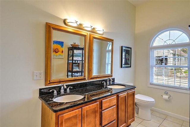 bathroom featuring tile patterned floors, toilet, double vanity, and a sink