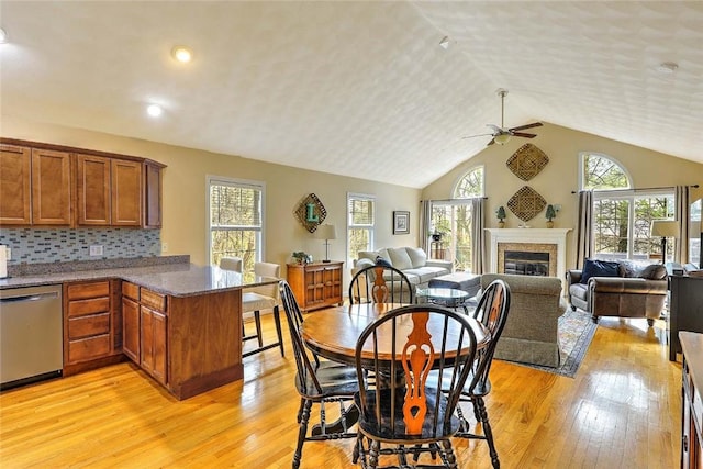 dining space featuring light wood-style flooring, a ceiling fan, a wealth of natural light, and vaulted ceiling