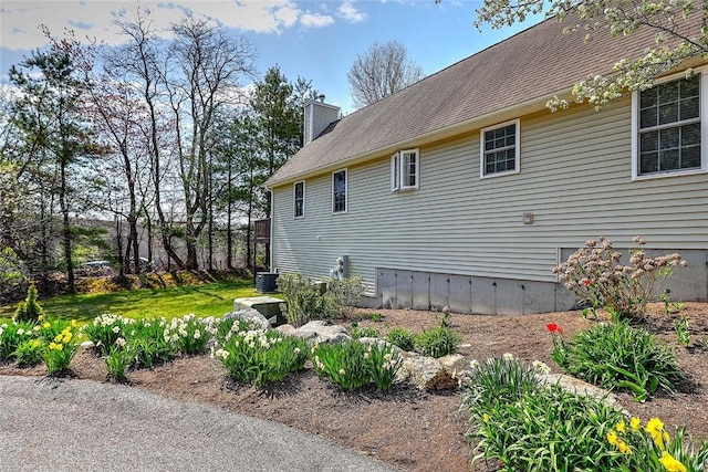 view of home's exterior featuring central AC and a chimney