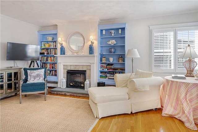 living area featuring a tile fireplace, wood finished floors, and crown molding