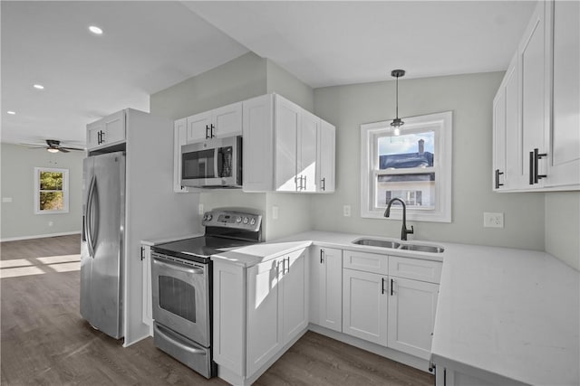 kitchen with stainless steel appliances, dark wood-style flooring, light countertops, and a sink