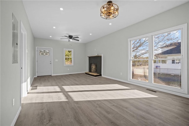 unfurnished living room featuring wood finished floors, visible vents, and a fireplace with raised hearth