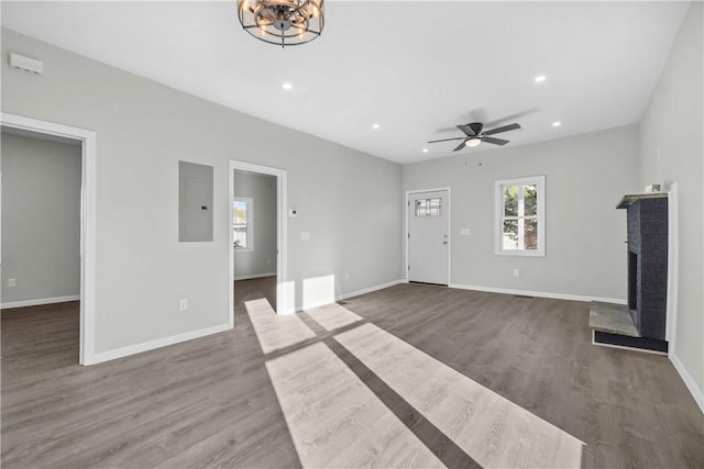 unfurnished living room featuring dark wood-style floors, ceiling fan, electric panel, and a fireplace