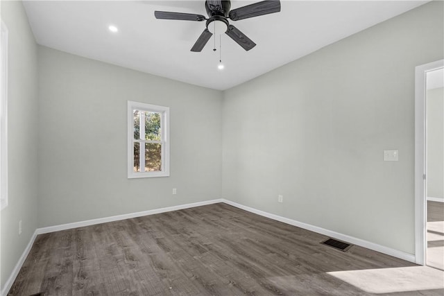 spare room with a ceiling fan, visible vents, wood finished floors, and baseboards