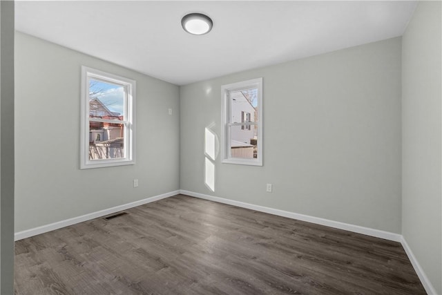 unfurnished room with dark wood-style floors, baseboards, and visible vents