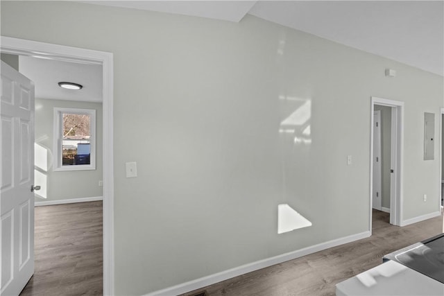 spare room featuring wood finished floors, electric panel, and baseboards