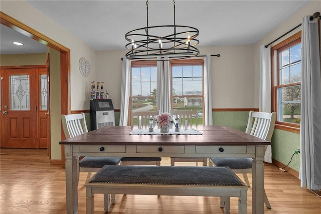 dining space with a chandelier, baseboards, and light wood finished floors