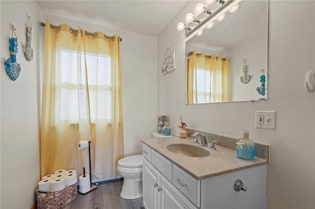 bathroom with wood finished floors, a wealth of natural light, toilet, and vanity