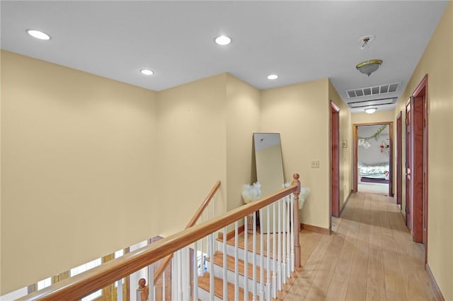 hall with recessed lighting, light wood-style flooring, an upstairs landing, baseboards, and visible vents