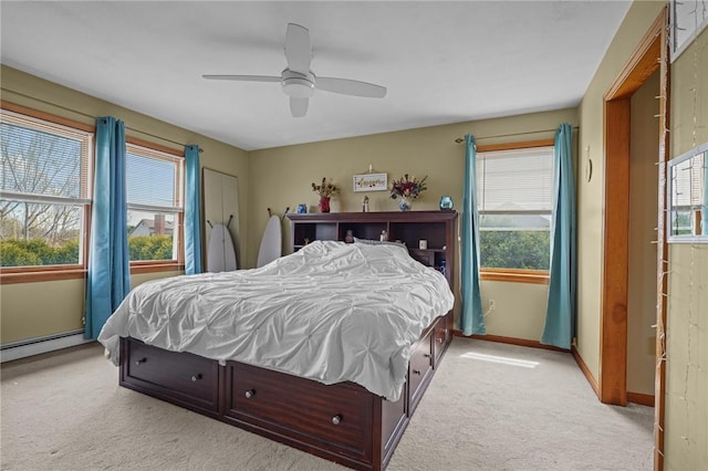 bedroom with ceiling fan, baseboards, a baseboard heating unit, and light carpet