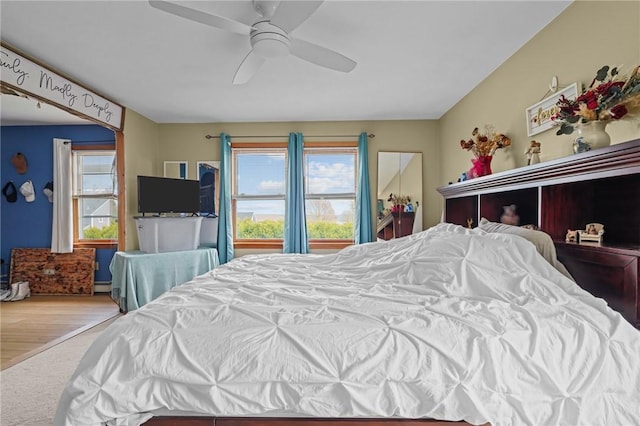carpeted bedroom featuring baseboard heating and a ceiling fan