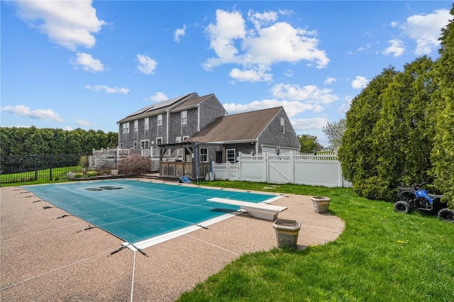 view of swimming pool with a patio area, a diving board, a yard, a fenced in pool, and a fenced backyard