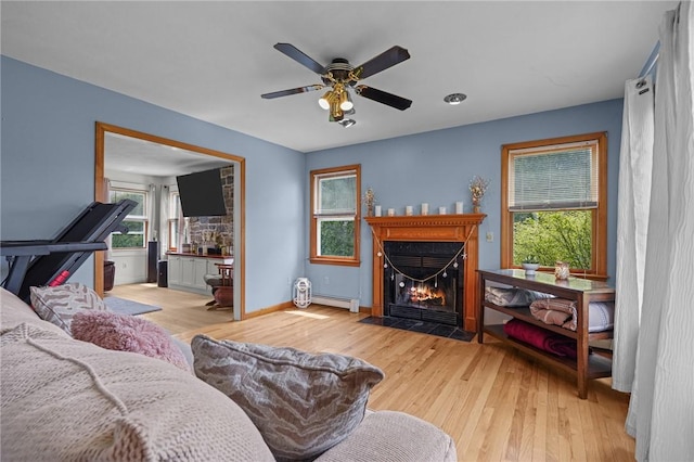 living room with a fireplace with flush hearth, ceiling fan, baseboards, wood finished floors, and a baseboard radiator