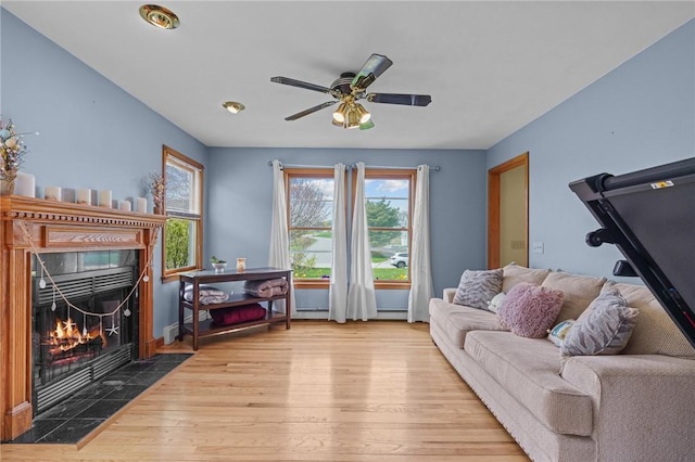 living area featuring ceiling fan, hardwood / wood-style floors, a high end fireplace, and baseboards