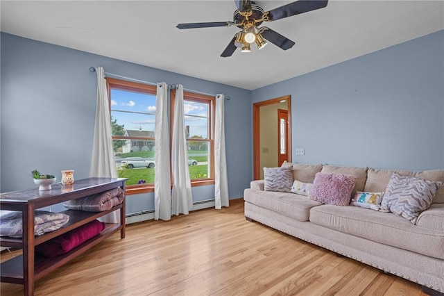 living room with a baseboard heating unit, ceiling fan, and light wood-style floors