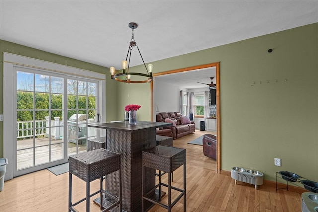 dining room featuring light wood finished floors, an inviting chandelier, and baseboards