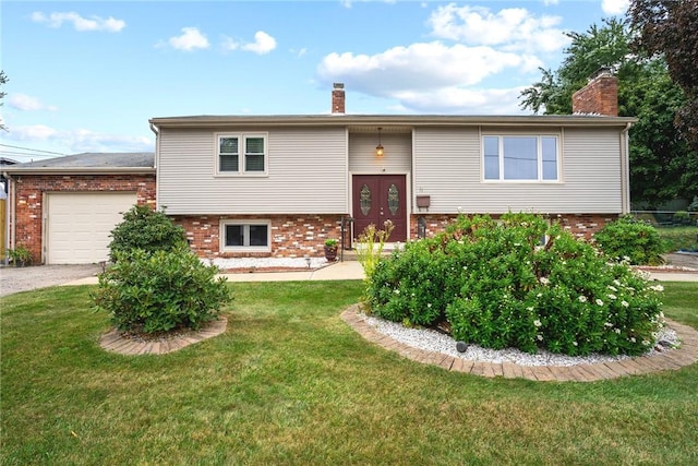 bi-level home featuring a chimney, brick siding, a garage, driveway, and a front yard
