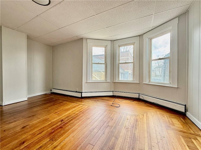 172 Park Ave, Woonsocket, RI 02895 - empty room featuring baseboards, baseboard heating, a drop ceiling, and hardwood / wood-style flooring