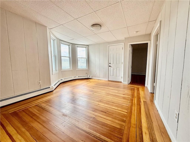172 Park Ave, Woonsocket, RI 02895 - unfurnished bedroom with baseboard heating, baseboards, a paneled ceiling, and light wood-type flooring