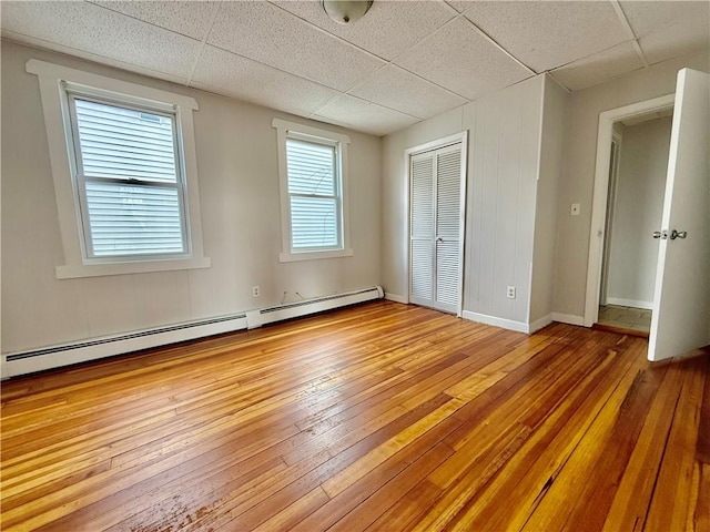 172 Park Ave, Woonsocket, RI 02895 - unfurnished bedroom with wood-type flooring, baseboard heating, and a paneled ceiling