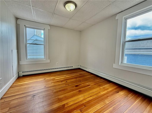 172 Park Ave, Woonsocket, RI 02895 - empty room with a baseboard heating unit, a drop ceiling, baseboard heating, and hardwood / wood-style flooring