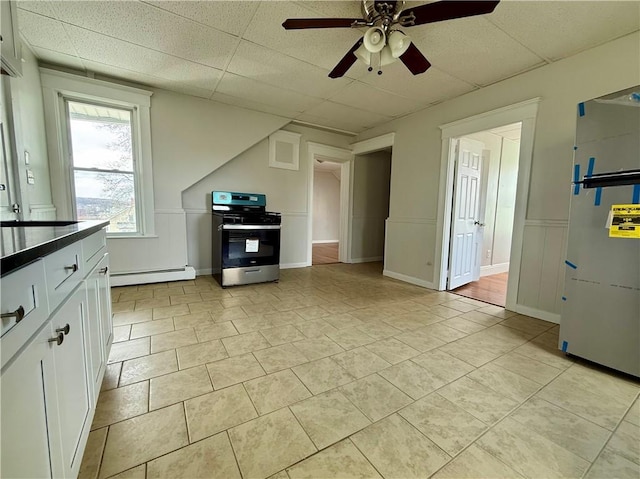172 Park Ave, Woonsocket, RI 02895 - kitchen featuring a ceiling fan, a paneled ceiling, stainless steel gas range oven, white cabinets, and a baseboard heating unit