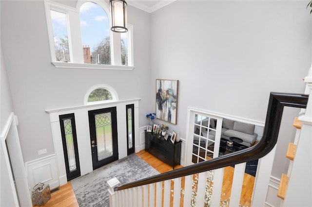 entrance foyer with wood finished floors, a high ceiling, and crown molding