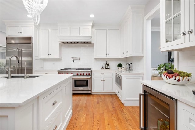 kitchen featuring decorative backsplash, light countertops, built in appliances, white cabinets, and wine cooler