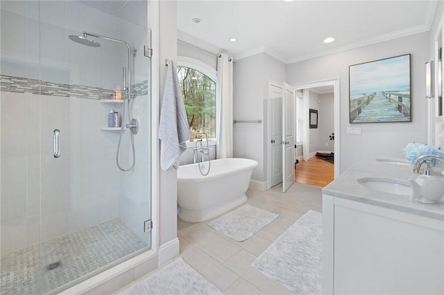 full bath with a sink, a shower stall, a freestanding tub, double vanity, and ornamental molding