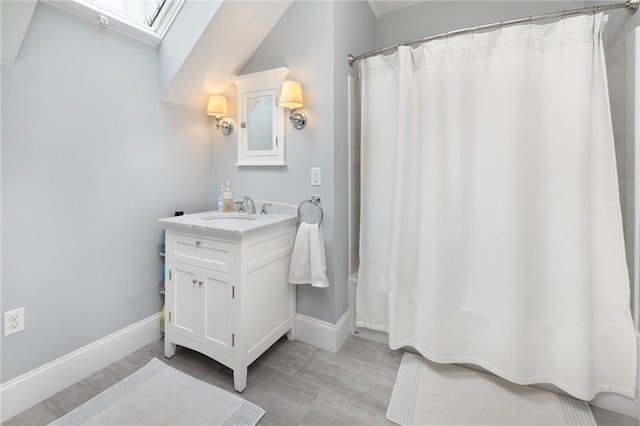full bathroom featuring vanity, baseboards, a shower with shower curtain, and a skylight