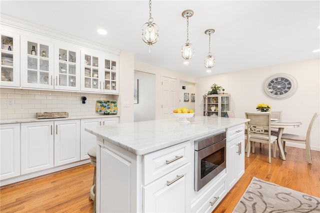 39 Greenbriar Rd, West Warwick, RI 02893 - kitchen with stainless steel microwave, pendant lighting, light wood-style flooring, and tasteful backsplash