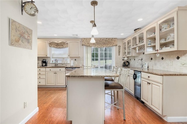 39 Greenbriar Rd, West Warwick, RI 02893 - kitchen featuring a sink, cream cabinetry, a breakfast bar, and glass insert cabinets