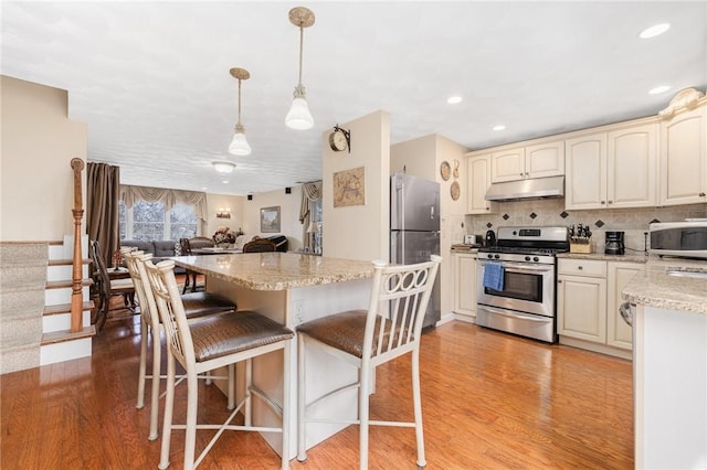39 Greenbriar Rd, West Warwick, RI 02893 - kitchen with under cabinet range hood, stainless steel appliances, open floor plan, and light wood-style flooring