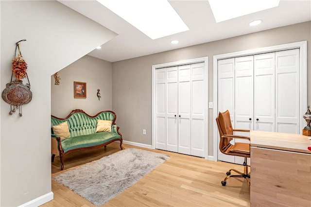 home office with recessed lighting, baseboards, wood finished floors, and a skylight
