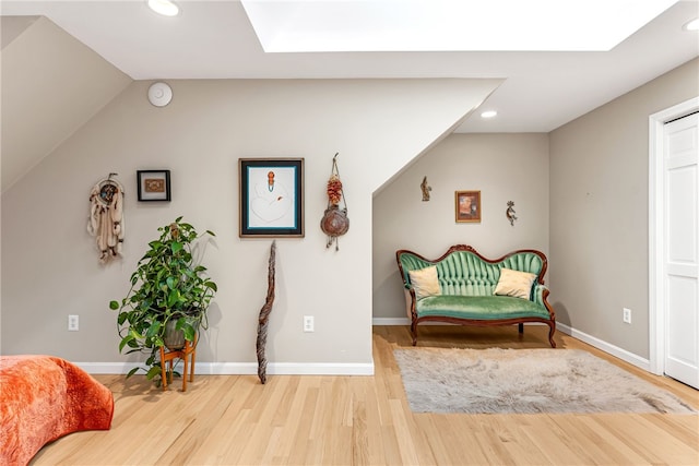 living area featuring recessed lighting, baseboards, wood finished floors, and vaulted ceiling with skylight