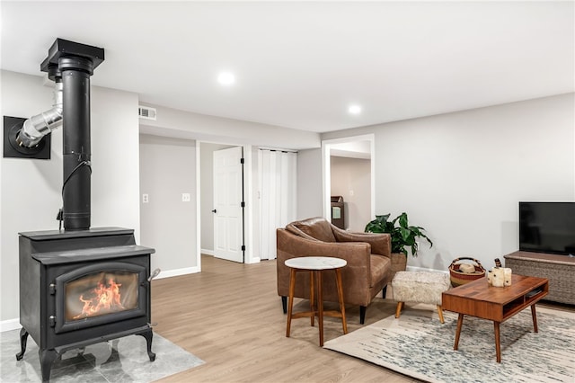 living area featuring visible vents, a wood stove, light wood-style floors, baseboards, and recessed lighting