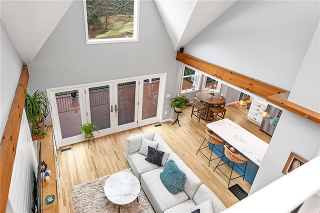 living area featuring french doors, visible vents, wood finished floors, high vaulted ceiling, and baseboards