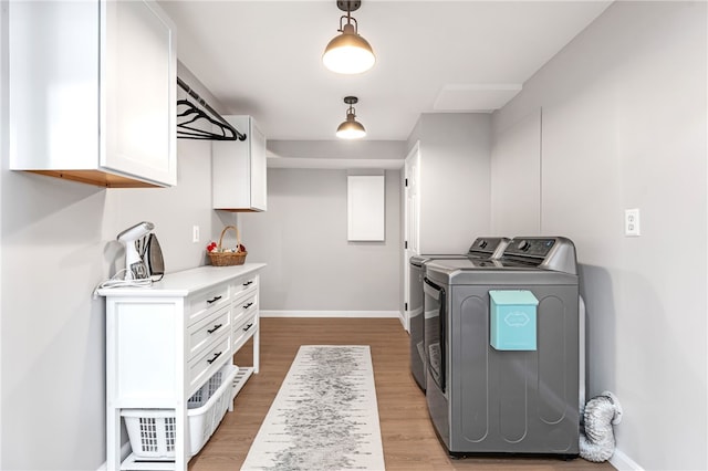 clothes washing area featuring baseboards, light wood finished floors, cabinet space, and washer and dryer