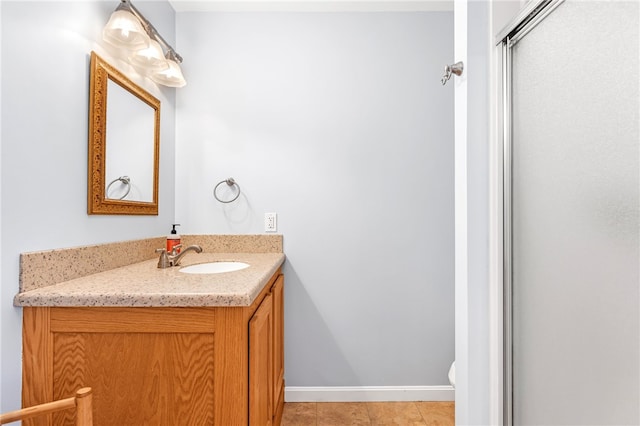 bathroom with vanity, tile patterned flooring, baseboards, and toilet
