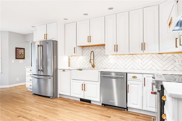 kitchen with appliances with stainless steel finishes, light countertops, white cabinetry, baseboards, and tasteful backsplash
