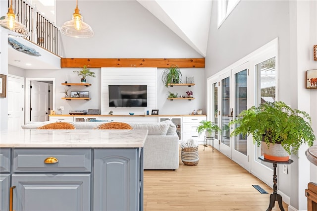 living area featuring visible vents, light wood finished floors, and a towering ceiling