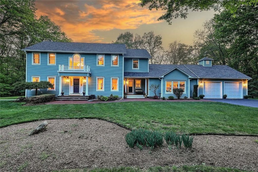 66 Tarklin Rd, Smithfield, RI 02814 - colonial house featuring an attached garage, asphalt driveway, a balcony, a front lawn, and covered porch